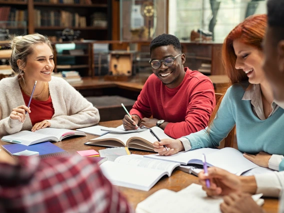 Students around a table with notebooks collaborating together