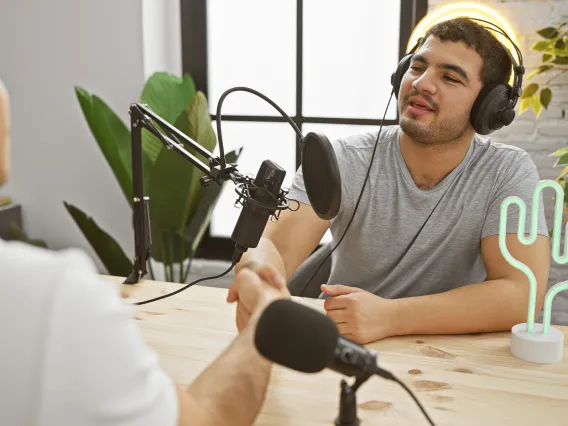 Two people with headphones create a podcast by a lit up cactus light