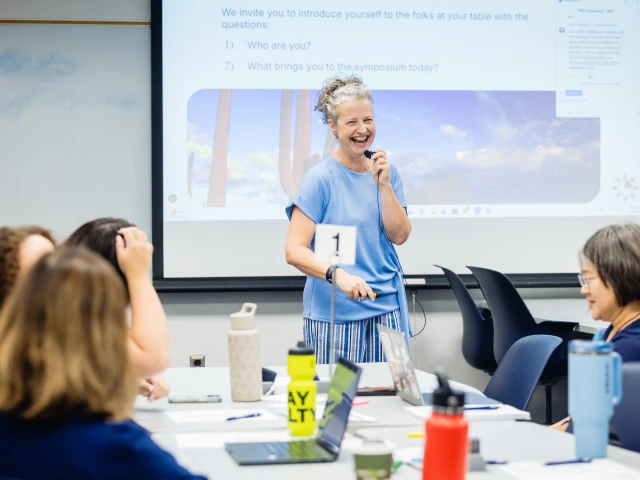 A woman is smiling and presenting to a group