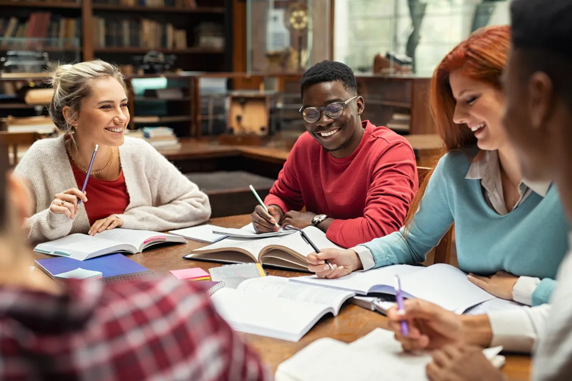 Students around a table with notebooks collaborating together