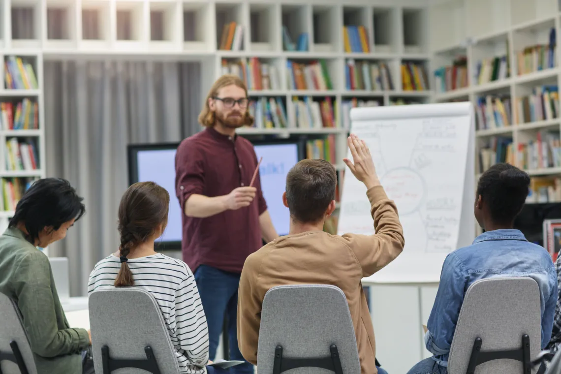 Teacher in front of students raising their hands