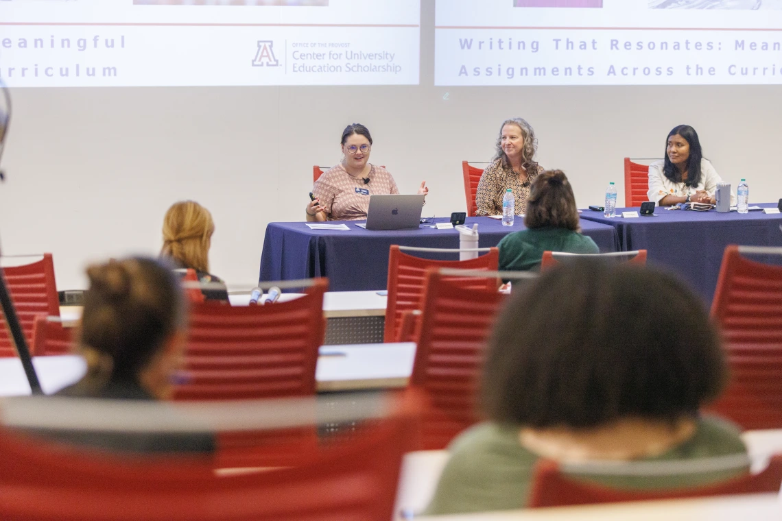 Three women sit at a panel table during a University of Arizona presentation on writing assignments.