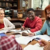 Students around a table with notebooks collaborating together